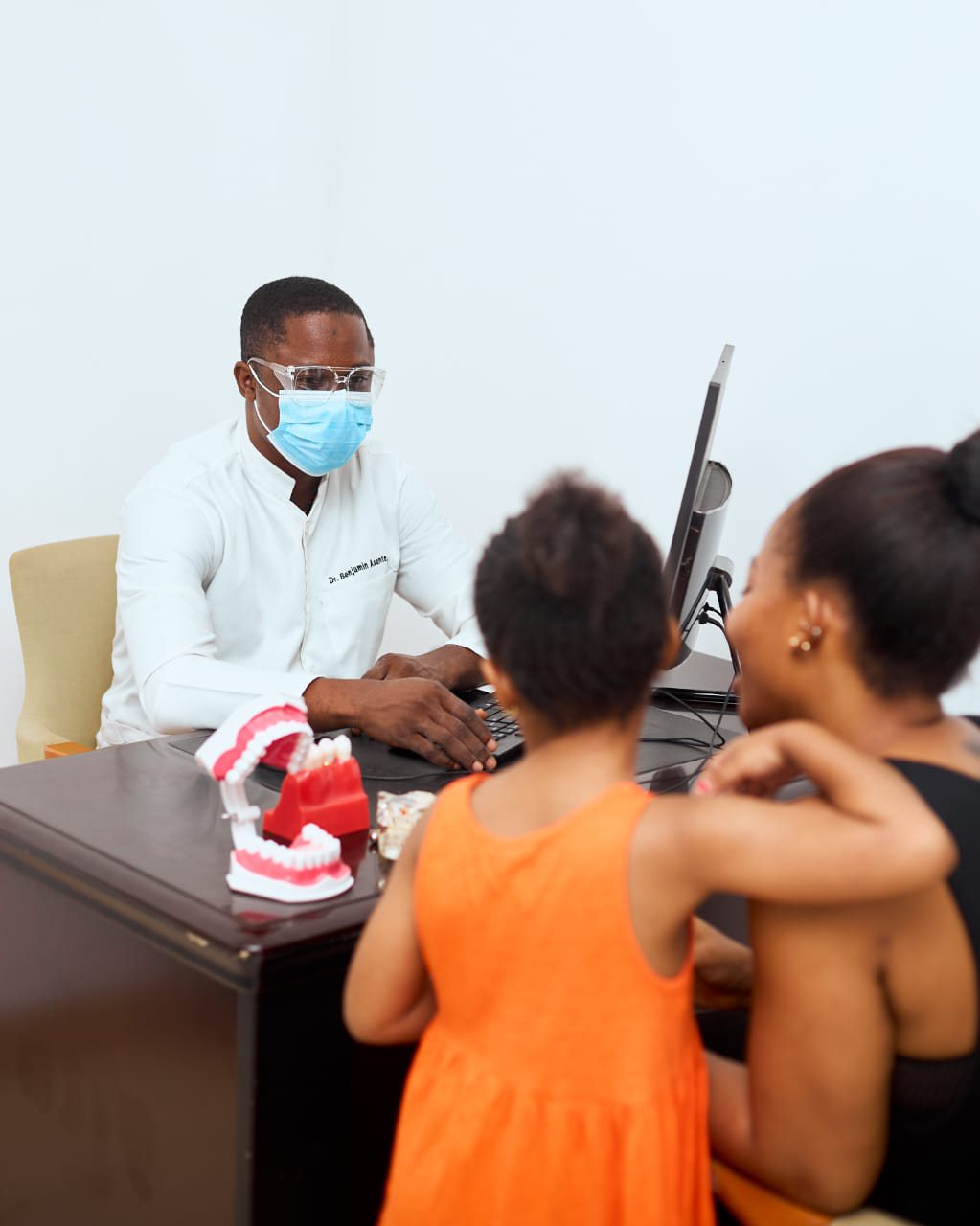 Dr. Asante explaining dental care to a mother and child